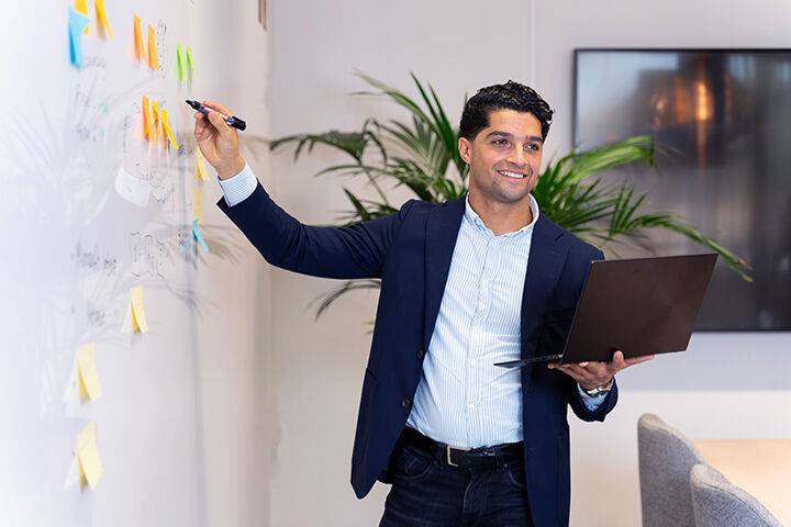 Workplace as a service medewerker brainstormt in vergaderruimte met laptop in de hand