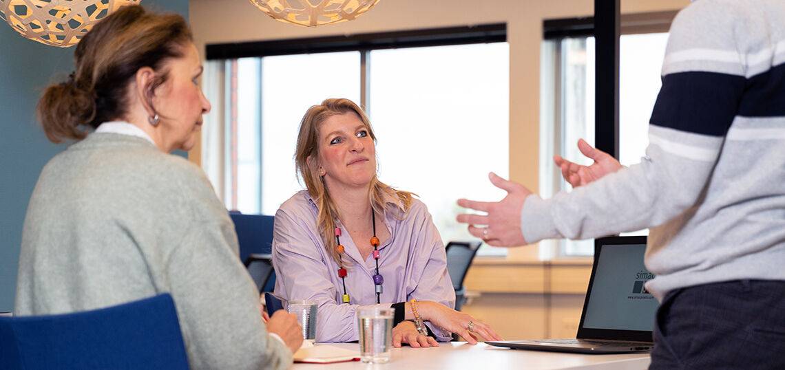 Medewerker die uitleg geeft aan twee collega's in kantooromgeving